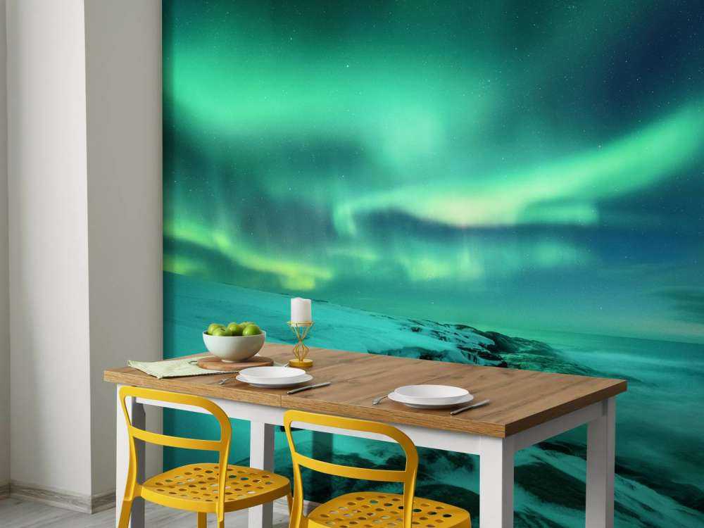 Zielone światła północne nad zaśnieżonymi skałami